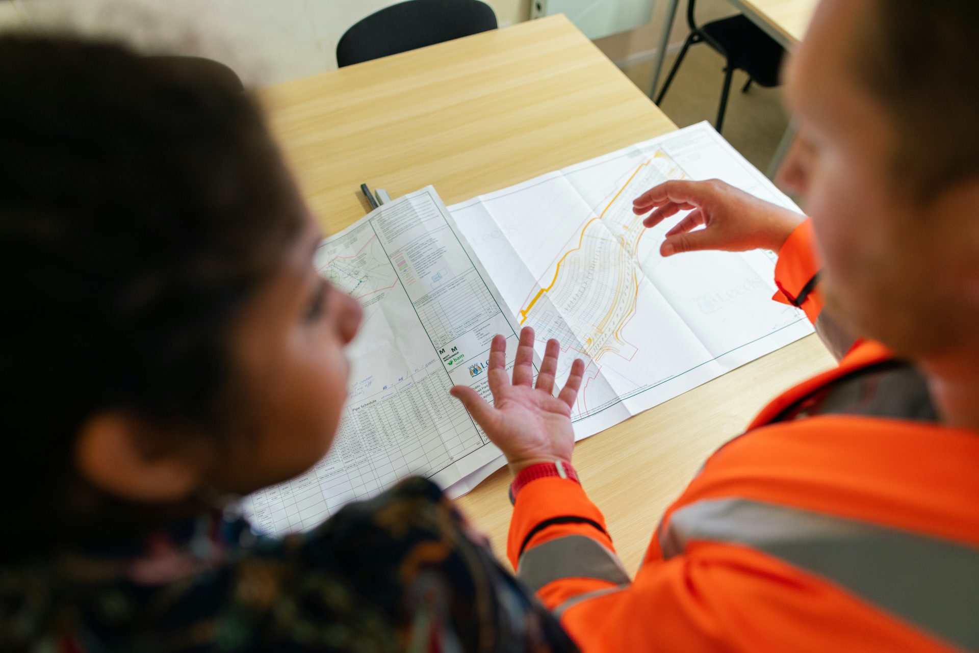 Two people discussing maps on table